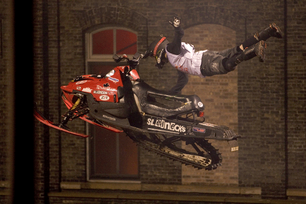 Lee Stuart mid-air on a snowmobile