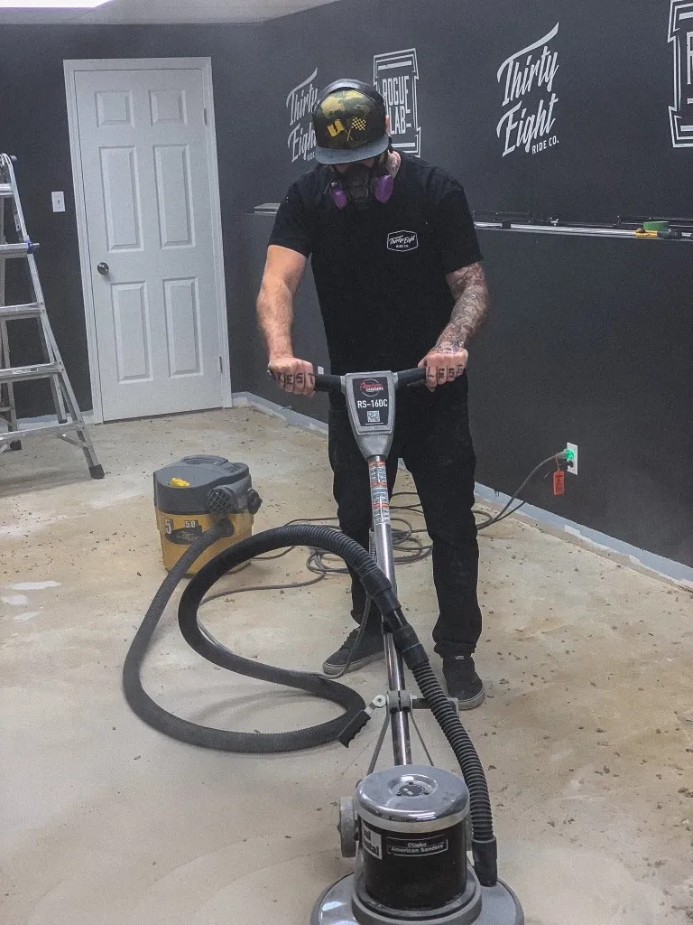 Lee Stuart sanding the basement floor while building the first print shop